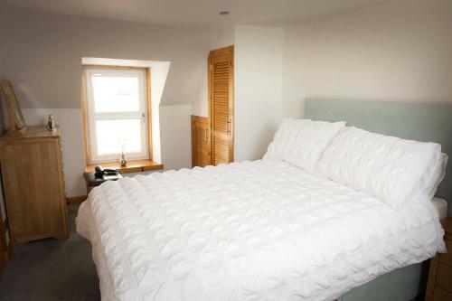 a bedroom with a large white bed with a window at Seafront holiday home in Findochty in Findochty