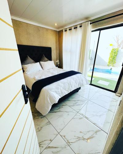 a bedroom with a bed and a large window at The Pool_deck apartment in Lebowakgomo