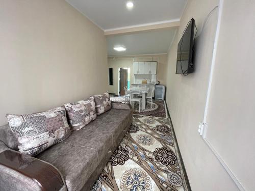 sala de estar con sofá y TV de pantalla plana en Guest House Ugra en Barskoon