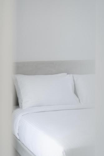 a white bed with white sheets and a pillow at Alegria by Casa Sigalas in Oia