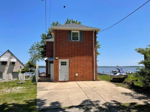 a red brick house with a driveway in front of the water at Waterfront Home with Private Beach, Stunning Views in Middle River