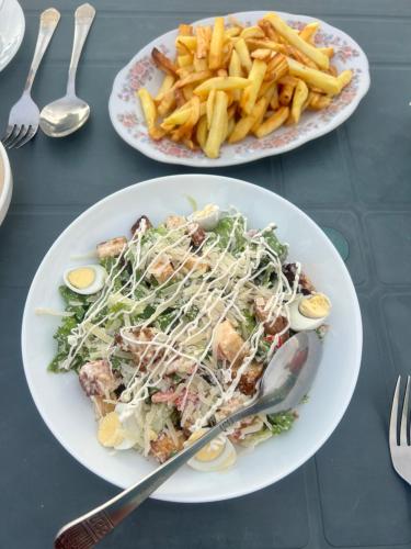 two plates of food with a salad and french fries at Inn David in Chakvi