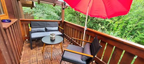 a balcony with two chairs and a red umbrella at Ferienwohnung Wildgatter in Grafenwiesen