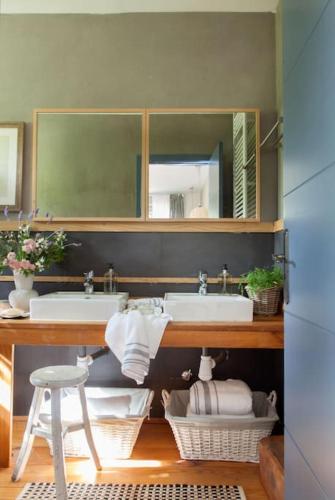a bathroom with two sinks and a mirror and a stool at Wishome-Finca de película en el campo con piscina privada in Mejorada