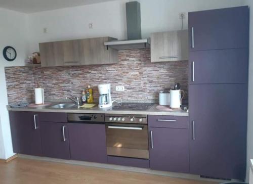 a kitchen with purple appliances and a brick wall at Bernsteinglück in Wunsiedel