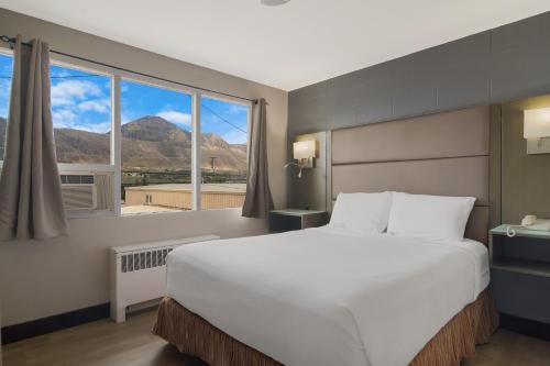 Canadas Best Value Inn & Suites Kamloops في كاملوبس: غرفة نوم بسرير كبير ونافذة كبيرة