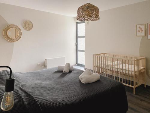 een slaapkamer met een wieg en een bed met kussens bij Beautiful Villa with swimming pool in Zonhoven in Genk