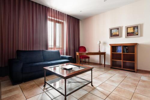 a living room with a blue couch and a table at Exe Alfonso VIII in Plasencia
