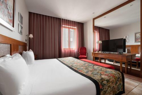 a hotel room with a large bed and a desk at Exe Alfonso VIII in Plasencia