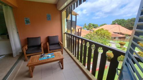 a balcony with two chairs and a table and a window at studio plage de l'anse caritan in Sainte-Anne