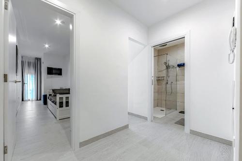 Habitación blanca con ducha a ras de suelo y baño. en Luxury 2bedroom apartment on San Juan Beach en Playa de San Juan