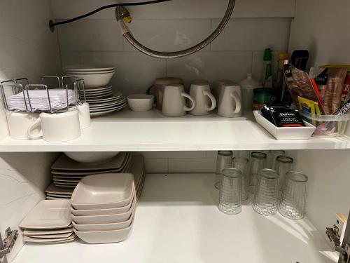 a kitchen shelf filled with plates and dishes at LETICE LODGE Chillán in Chillán