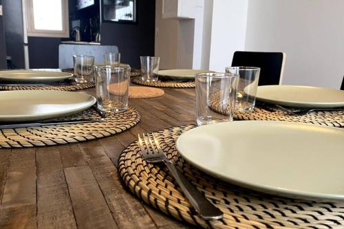 a table with plates and glasses on a wooden table at * 3 Chambres - Haut de gamme - proche Paris * in Villejuif