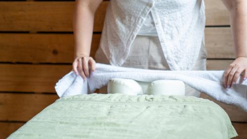a woman is rolling towels onto a bed at Le Village de la Champagne - Slowmoov in Bar-sur-Aube