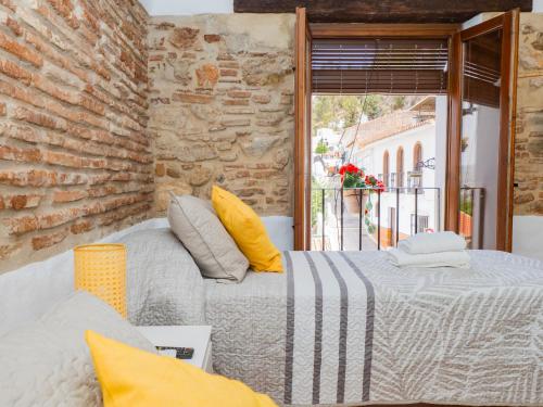 a bedroom with two beds and a brick wall at Cubo's La Casa del Arco Room Granada in Cártama
