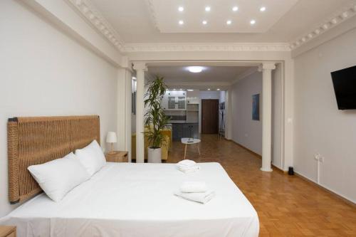 a bedroom with a white bed and a kitchen at Hestia Apartment! in Thessaloniki