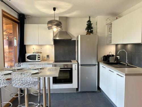 Il comprend une cuisine équipée d'un réfrigérateur et d'une table avec des chaises. dans l'établissement Les Gets - Appartement rénové 3 étoiles, face aux pistes, balcon et parking - FR-1-623-294, aux Gets