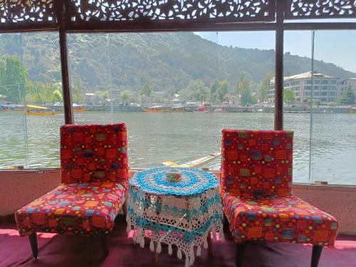 two chairs and a table in front of a body of water at Hotel Island in Srinagar