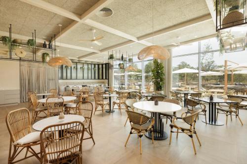 un ristorante con tavoli, sedie e finestre di Verdelago Resort a Praia Verde