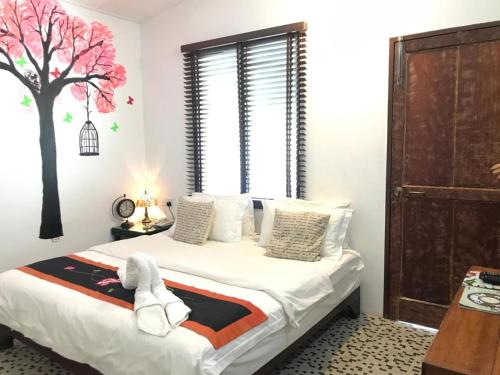 a bedroom with a bed with a tree on the wall at RANGOON RESIDENCES + in George Town