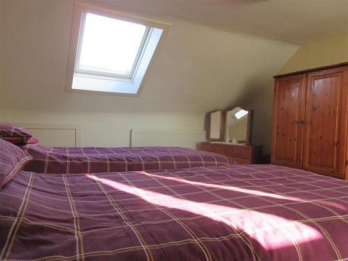 a bedroom with a purple bed and a window at Ailsa Cottage in Newton Stewart