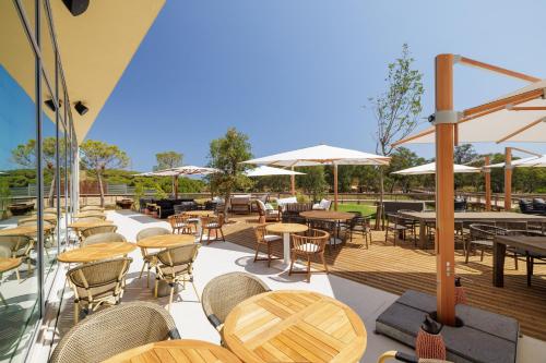 un patio esterno con tavoli, sedie e ombrelloni di Verdelago Resort a Praia Verde