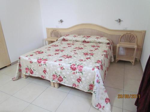 1 dormitorio con 1 cama con colcha de flores en Villaggio Hotel Agrumeto, en Capo Vaticano