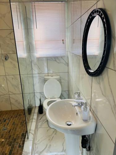 a bathroom with a sink and a toilet and a mirror at The Pool_deck apartment in Lebowakgomo