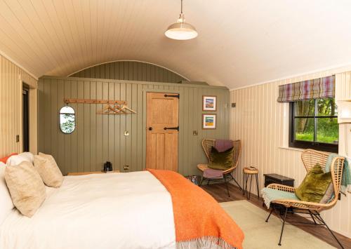 a bedroom with a bed and two chairs at The Hide at Woodside in St. Andrews