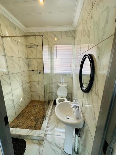 a bathroom with a toilet and a sink and a shower at The Pool_deck apartment in Lebowakgomo