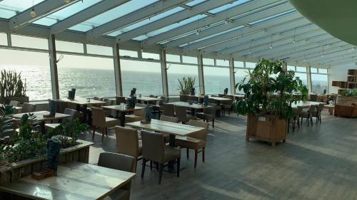 un restaurant avec des tables et des chaises et l'océan dans l'établissement De Pier Suites, à Scheveningen