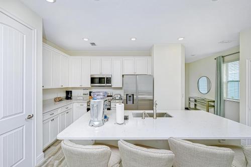 a kitchen with white cabinets and a counter with chairs at Margaritaville Cottages Orlando with H2O Waterpark by Rentyl in Kissimmee