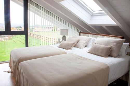 um quarto com 2 camas brancas e uma grande janela em Villa sublime con piscina climatizada y vistas em Prellezo