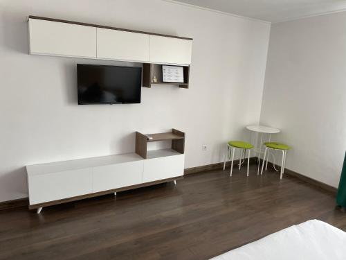 a living room with a tv and two green stools at Paula Apartment & Rooms in Oradea