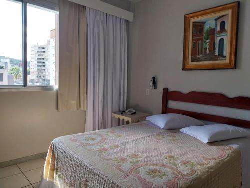 1 dormitorio con cama y ventana en Colle Tourist Hotel, en Criciúma