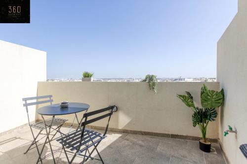 uma pequena mesa e cadeiras numa varanda com plantas em Spacious, 1BR duplex off UNI/Hospital with WIFI by 360 Estates em Msida
