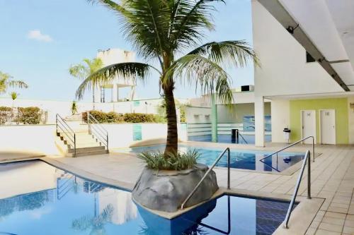 a swimming pool with a palm tree in a house at Flat Pertinho do Hot Park (200m)! Aconchegante! in Rio Quente