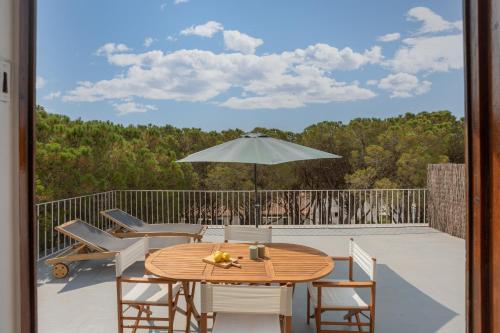 uma mesa de madeira com cadeiras e um guarda-sol num deque em Apartamentos CASA MAREA Calella Palafrugell con Parking em Calella de Palafrugell