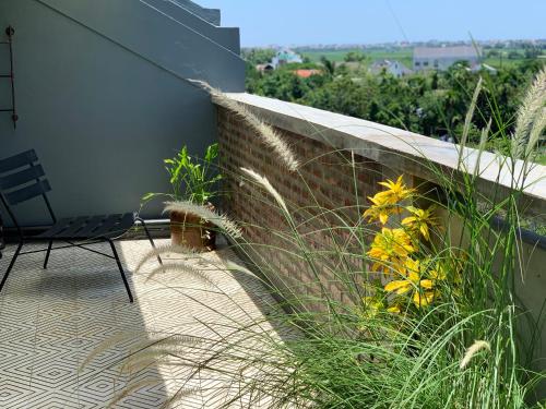 a patio with a chair and some tall grass at Kaia Gallery Hotel Hoi An in Hoi An