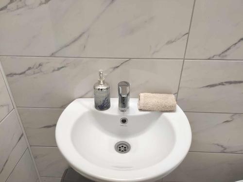 Baño con lavabo blanco y paredes de mármol en Hostel Horgos Centar, en Horgoš