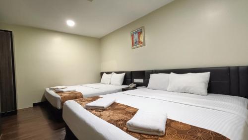 um quarto de hotel com duas camas com almofadas brancas em The Corum View Hotel em Bayan Lepas