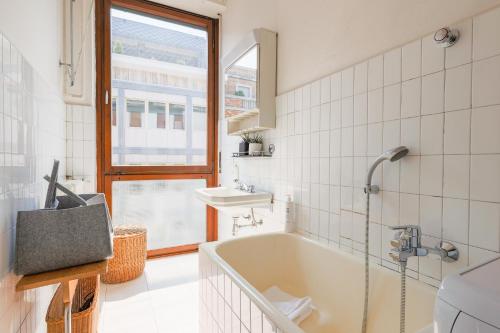 a bathroom with a tub and a sink and a window at Piazza Cavour Lake View - by MyHomeInComo in Como