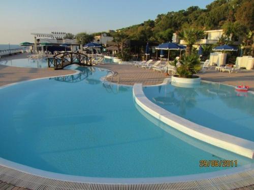 una gran piscina azul con sillas y sombrillas en Villaggio Hotel Agrumeto, en Capo Vaticano