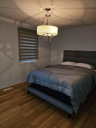 1 dormitorio con cama y lámpara de araña en Beautiful Home Away From Home, en Winnipeg