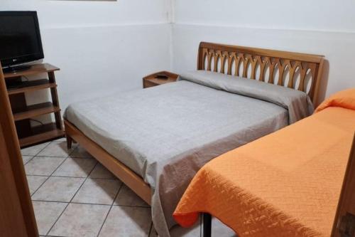 a bedroom with two beds and a tv on a tiled floor at Casa Erre in Lusciano