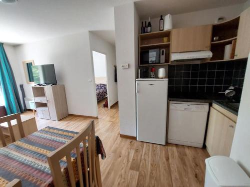 une cuisine avec un réfrigérateur blanc et une table dans l'établissement Les Jardins de Ramel -appart.T2, à Luchon