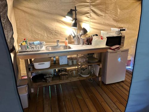 a kitchen in a tent with a sink and a refrigerator at Langø Feriecenter - Outdoor Lodge in Nakskov
