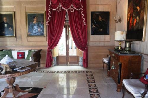 Palazzo Lupis B & B Grotteria Calabria Italia في Grotteria: غرفة معيشة مع ستائر حمراء وأريكة وطاولة