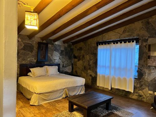 1 dormitorio con cama y pared de piedra en Hotel Chipinque en Monterrey