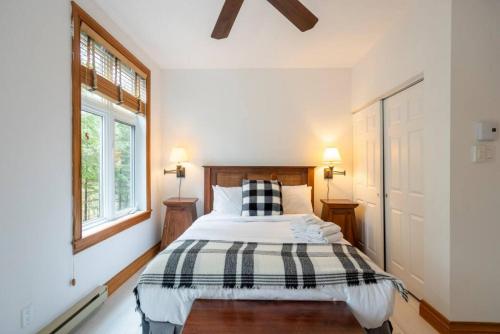 1 dormitorio con 1 cama con manta blanca y negra en 155 Falaise - Forest Chalet in Old Village Mont Tremblant, en Mont-Tremblant